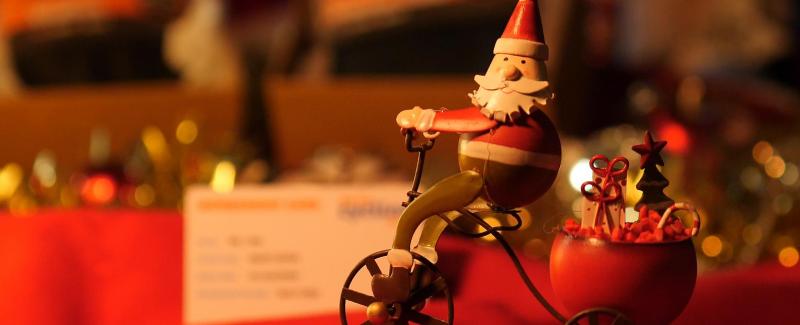 A wooden Santa toy in front of a low-lit festive scene