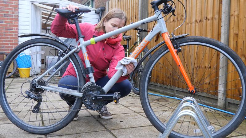 A woman is wiping down the down tube of a pinnacle bicycle