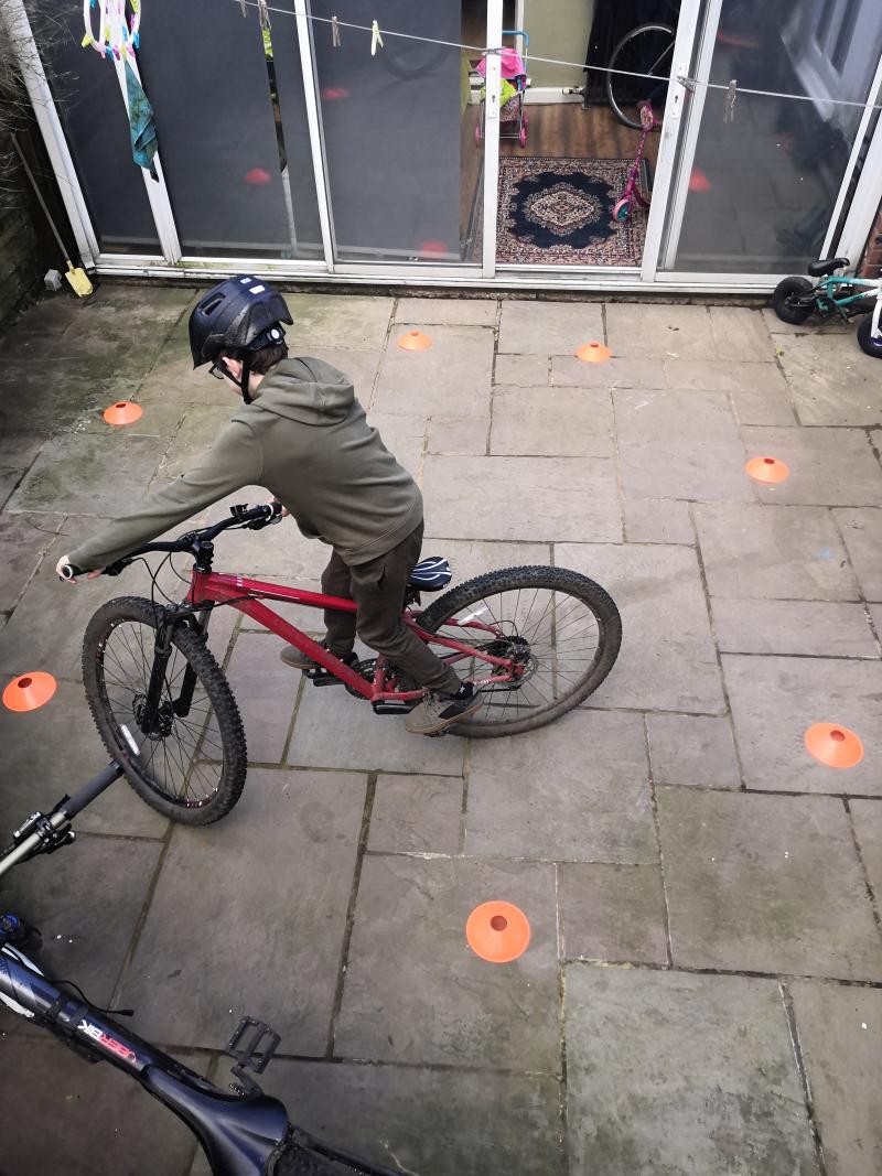 A boy on a mountain bike riding between some cones