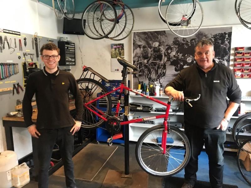 Two mechanics with a repaired bike in a bike shop