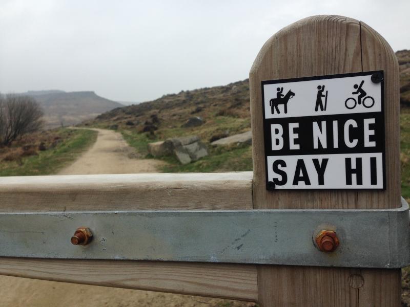 Be Nice Say Hi sign on a moorland track