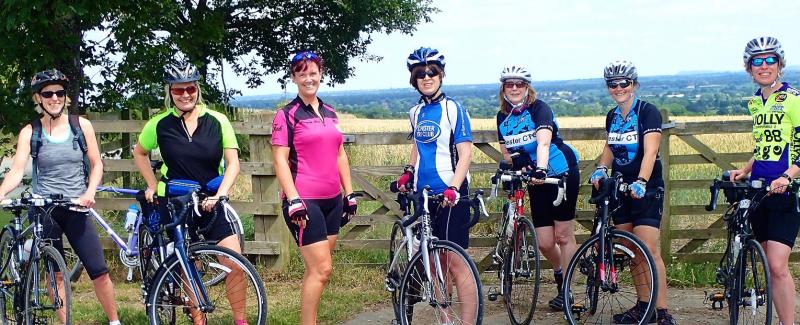 A group of women with their bikes in front of a countryside scene