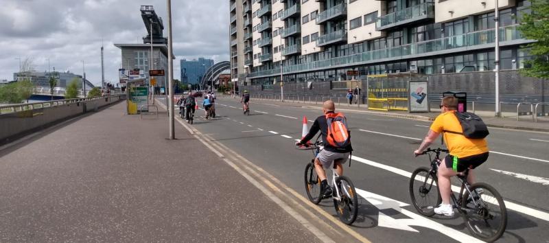 People cycling along a temporary cycle lane marked with cones