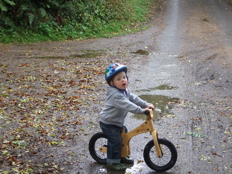 A toddler in a bright blue hat on a balance bike