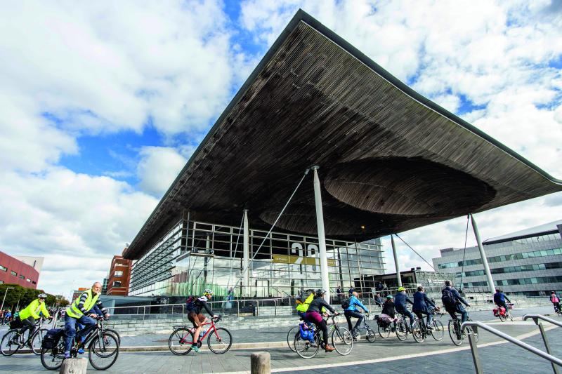 Lots of cyclists ride past the Senedd, home of the Welsh government