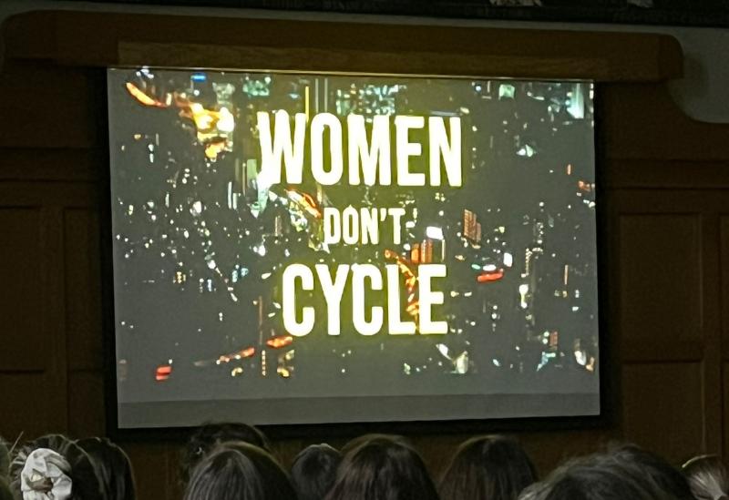 Title card of the documentary being shown on a projector featuring the words 'Women Don't Cycle'
