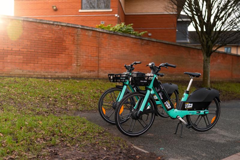 Two green TIER e-cycles sit side by side outside hospital