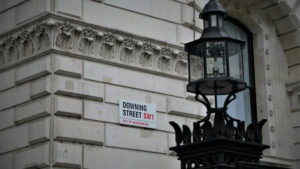 A photo of the street sign for Downing Street, with a decorative lamp post in the foreground