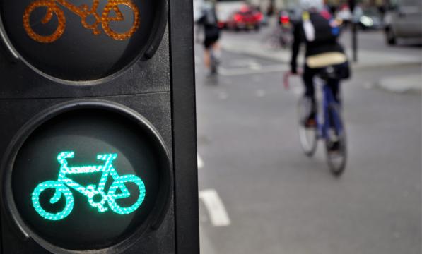Cyclist going through green cycle lane light 