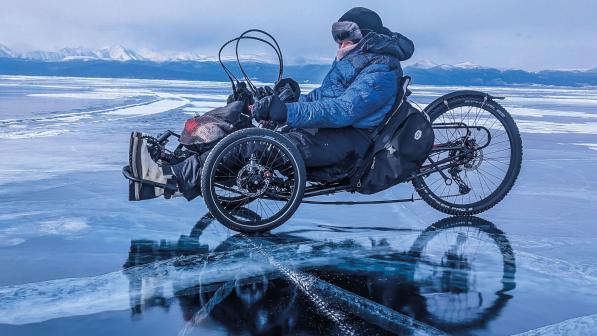A woman in warm gear is on a trike on a frozen lake