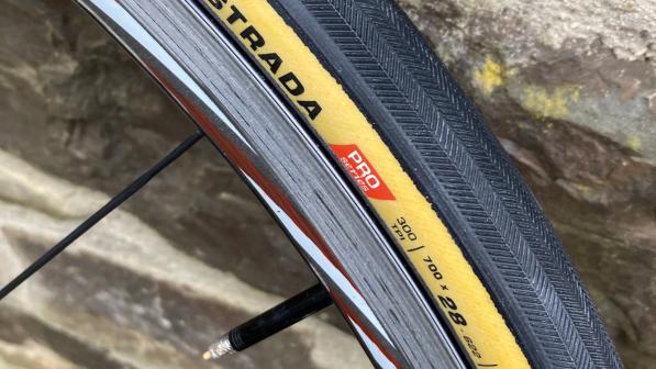 A section of the Challenge Strada Pro tyre on a bike wheel leaning against a brick wall