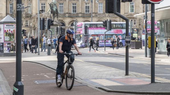 Man cycling on a cycle lane through an urban built up area