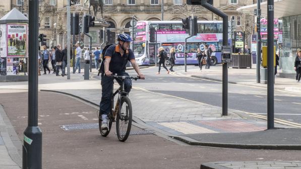 Man cycling on a cycle lane through an urban built up area
