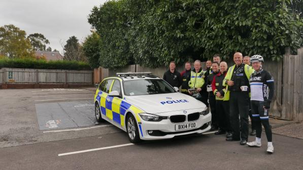 A group of police officers gathered around a marked police vehicle in a residential street