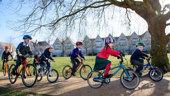 A group of school children cycle along a country park path together