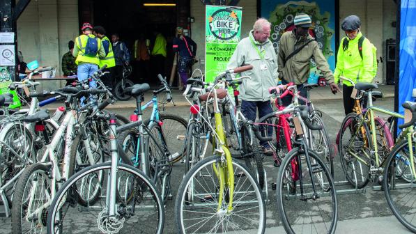 A large selection of second-hand bikes, showing all different types and colours. You can see road bikes, hybrids, mountain bikes. There are people in the background looking at the bikes