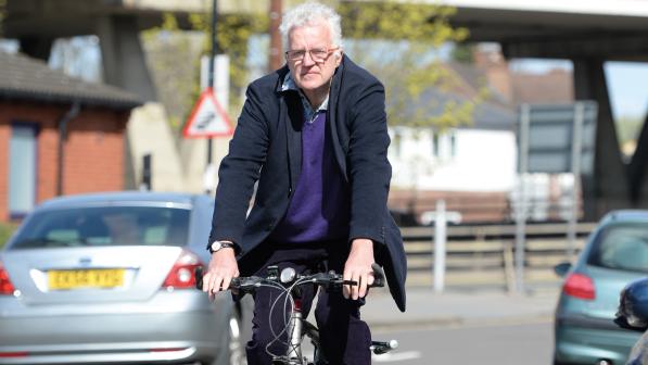 A man in normal clothing is cycling on an urban street