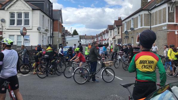 A large group of people are cycling on the road. There is a wide range of bikes and diversity of people