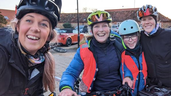 Three women pose for a selfie with a young girl. They're wearing cycle helmets