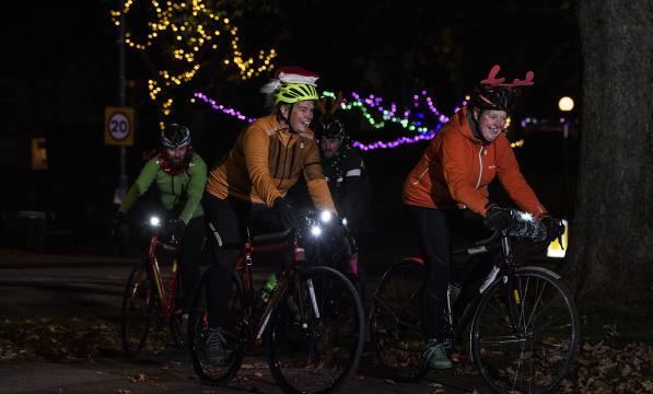 Cyclists riding at night wearing Christmas outfits. 