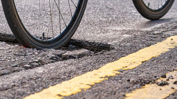 A bike going over a pothole on an urban road with double yellow lines