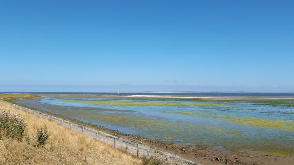 A landscape shot from a vantage point, with a flat sea and blue sky