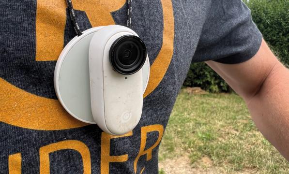 A white cycling camera worn around the neck