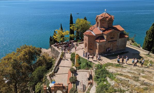 Looking down on a red brick church on a cliff top overlooking a blue sea