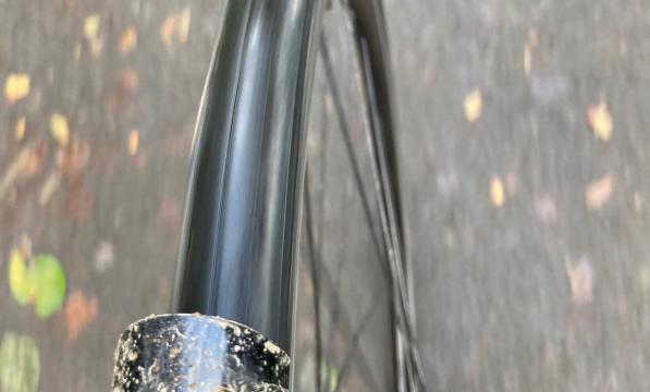A close-up of a bike wheel from  the top as the bike is being ridden along a path. There's mud on the mudguard