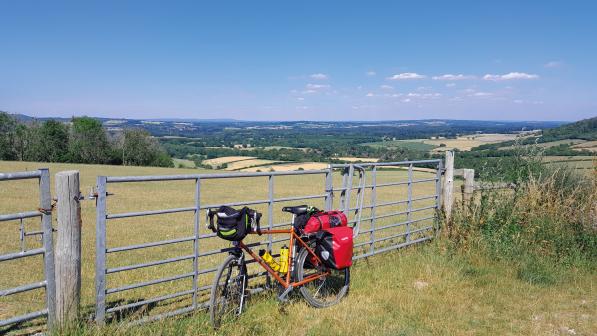 Bike leaning up against a metal fence next to a field on the South Downs Way