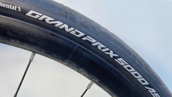A close-up of a bike tyre showing the tyre model: Grand Prix 5000 AS