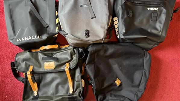 Five cycling panniers arranged on a floor with a red carpet