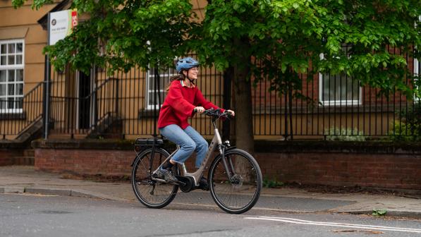 Woman in a red jumper cycling an ebike on the road (c) JoeCotterill/CyclingUK