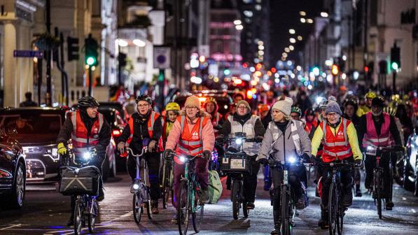 A large group of women are cycling through an urban landscape at night