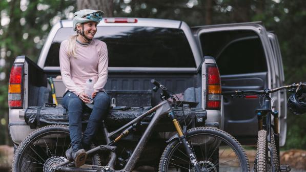 Georgia Leslie, nominated as a community champion in Cycling UK’s 100 Women in Cycling 2024, sitting on the back of a flatbed truck with her legs over a bike