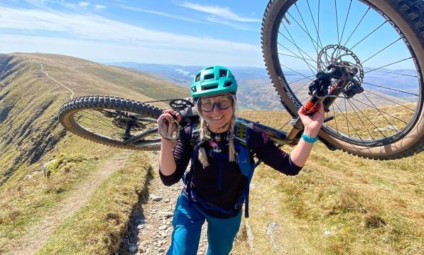 Kate O'Callaghan walking up a hill while holding her bike .jpg