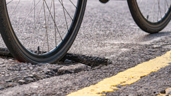 A bike wheel moving through a pothole in a road. 