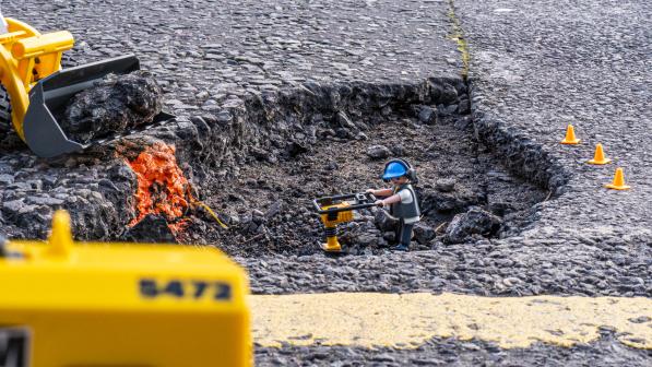 Playmobile construction worker toy placed in a large pot hole (c) Robert Spanring