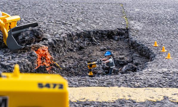 Playmobile construction worker toy placed in a large pot hole (c) Robert Spanring