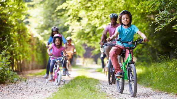 A family is riding on a trail through woods