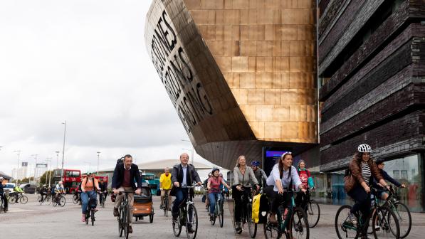 A large group of people are cycling round the Senedd building in Cardiff