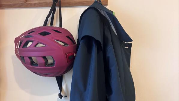 A blue jacket hanging up next to a pink cycle helmet