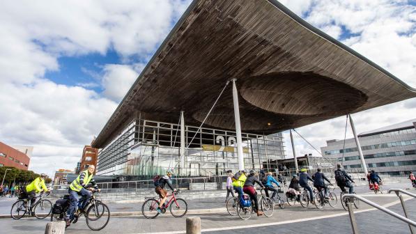 A group of people are cycling around the Welsh Parliament building in Cardiff