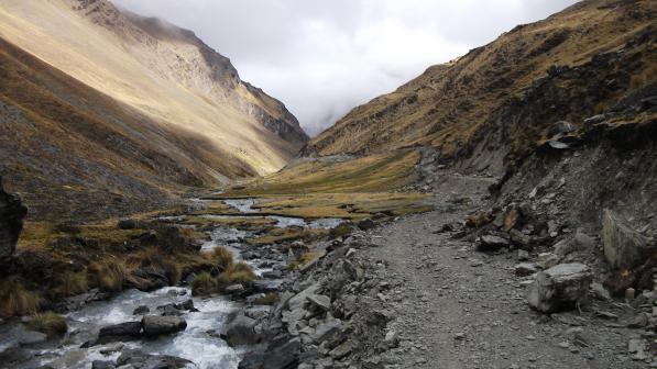 A mountain valley with rocky gravel track and a stream running alongside