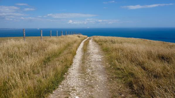 Gravel track heading towards blue sea