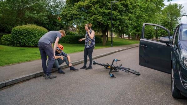 Injured cyclist sitting by the side of the road