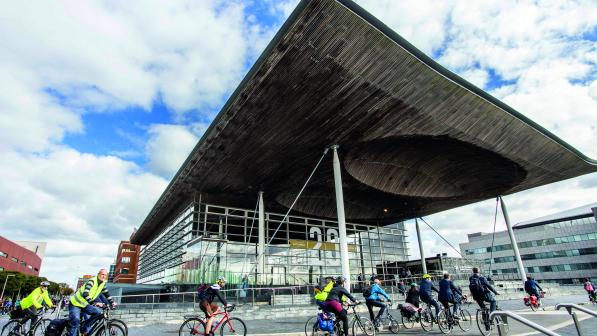Lots of cyclists ride past the Senedd, home of the Welsh government