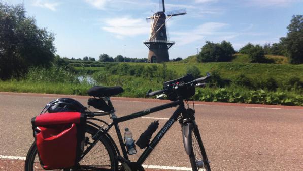 A bike parked on an empty cycle lane next to a windmill