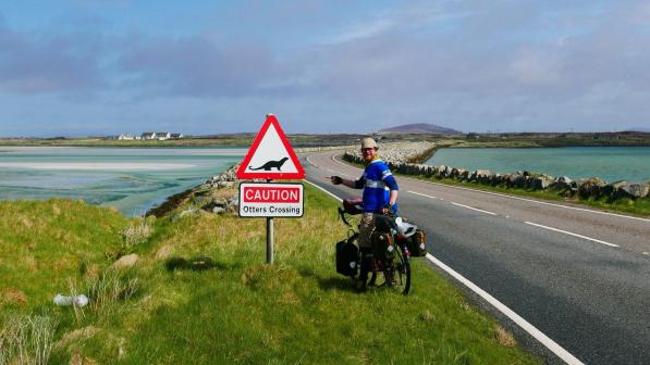 Cyclist by otters crossing sign in Outer Hebrides