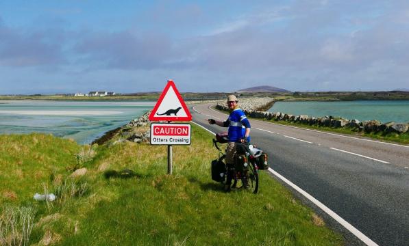 Cyclist by otters crossing sign in Outer Hebrides
